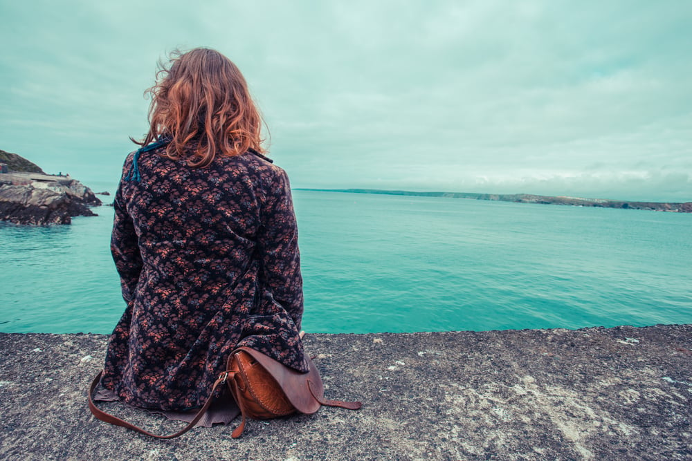 Una giovane donna è seduta in riva al mare in un porto