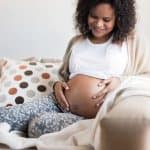 Gravidanza dopo aborto: donna incinta seduta a casa con mano sul ventre