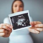 felice giovane donna incinta in possesso di ultrasuoni