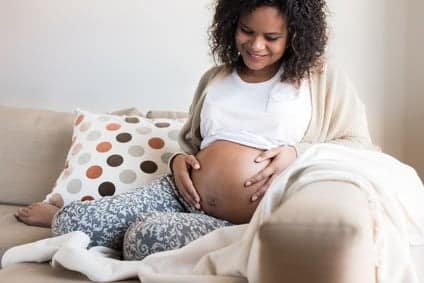 Gravidanza dopo aborto: donna incinta seduta a casa con mano sul ventre
