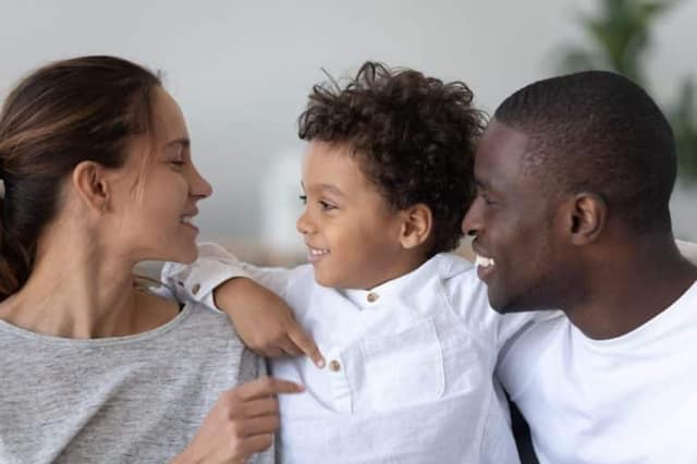 -giovani-genitori-multietnici-sorridenti-abbracciano-le-coccole-con-il-piccolo-figlio-birazziale-carino-a-casa