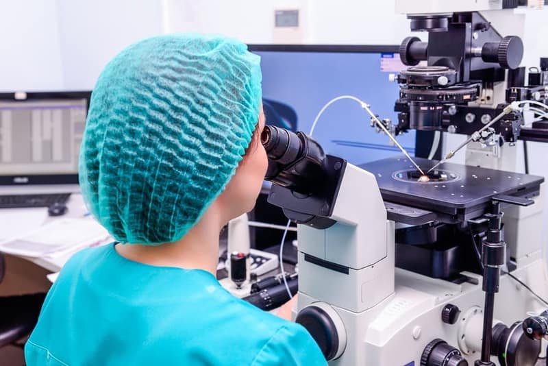 Embriologo che aggiunge sperma all'uovo nel laboratorio della clinica riproduttiva
