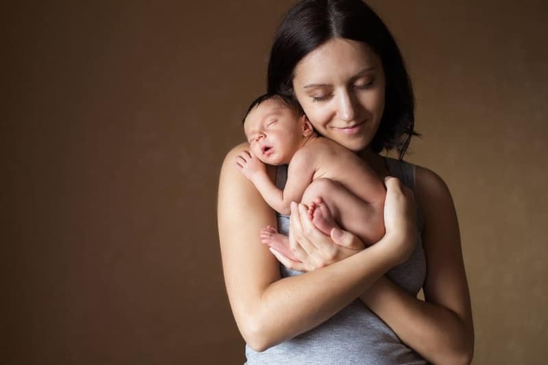 Giovane madre che tiene il suo neonato addormentato