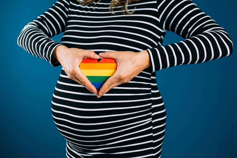 Primo piano della donna incinta che tiene un focolare colorato arcobaleno